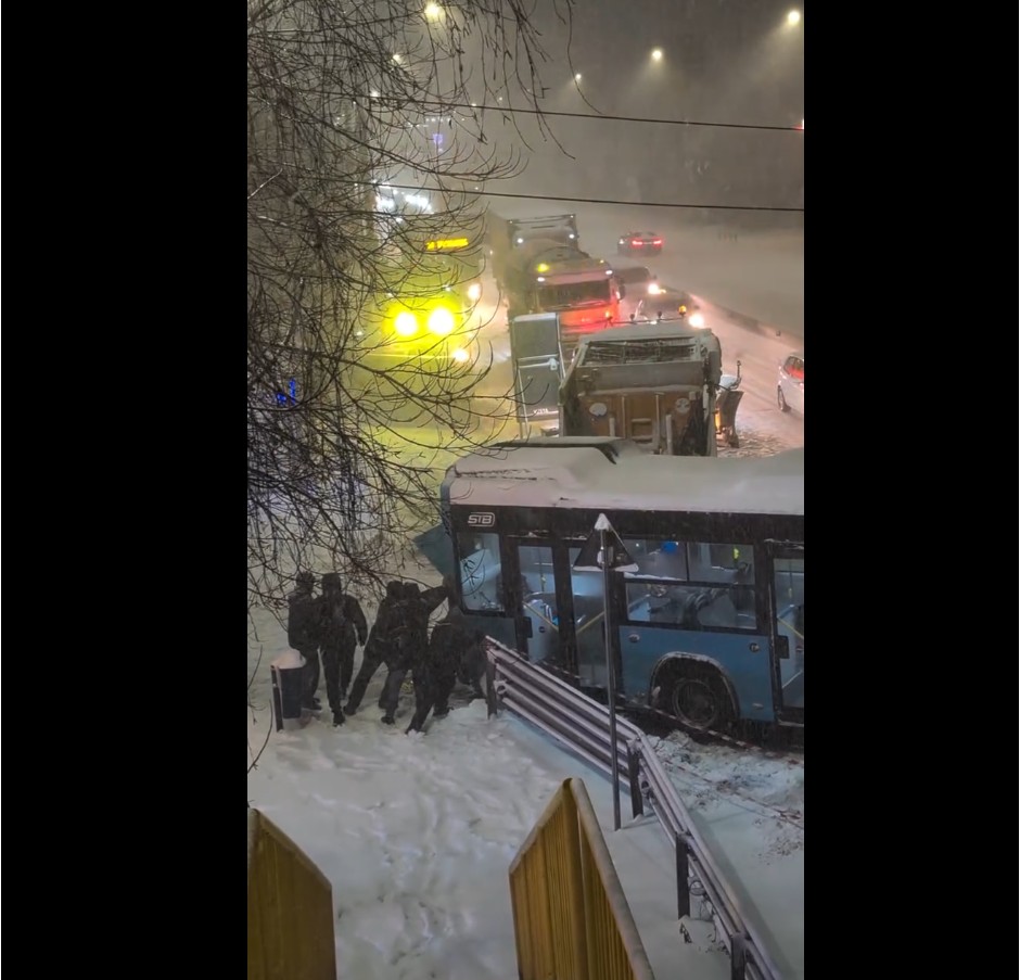 Imagini cu un autobuz STB ajuns într-un gard din cauza zăpezii. Câţiva oameni încearcă să-l împingă cu mâinile