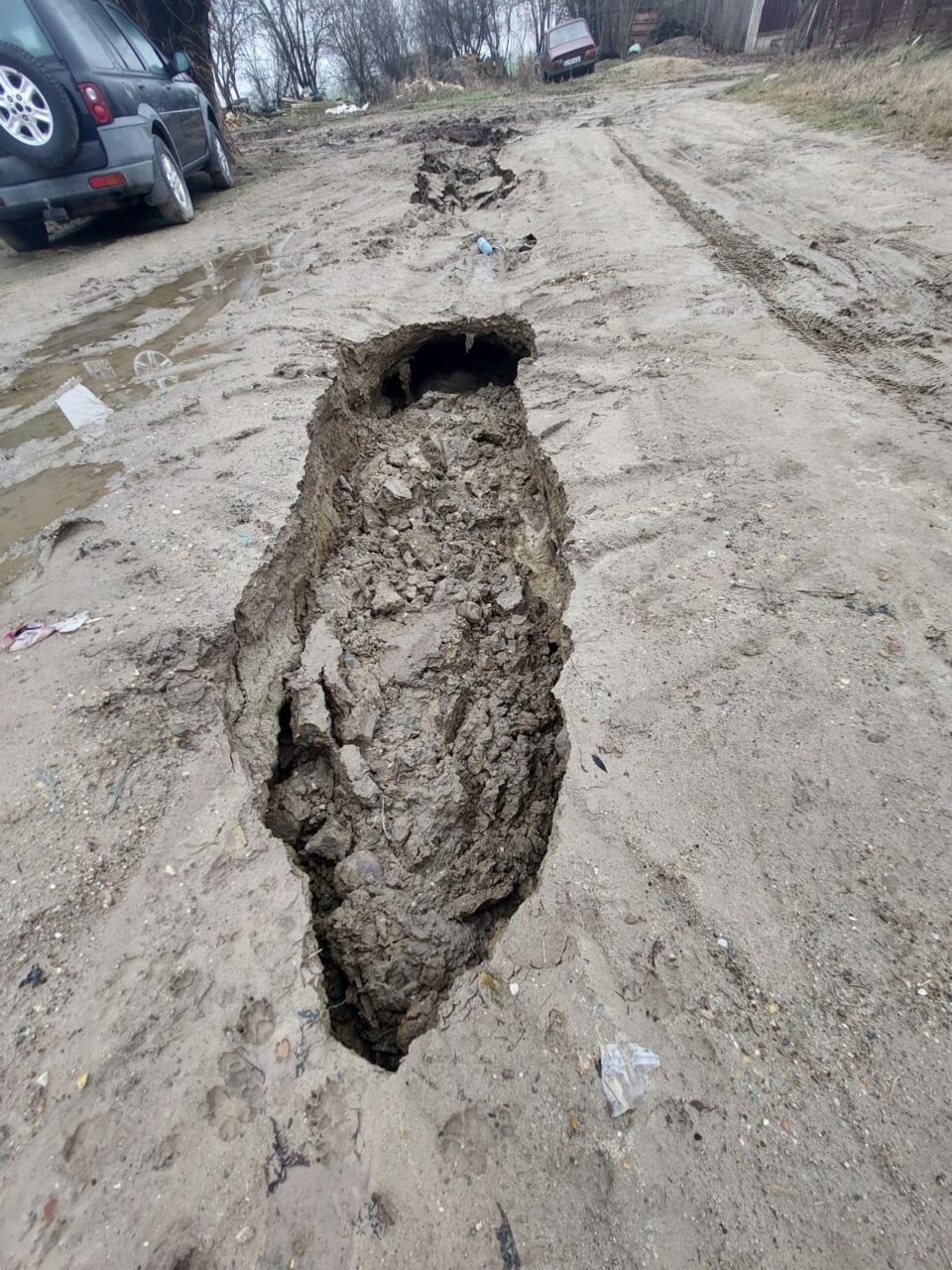Situație disperată pentru locuitorii din satul Basarabi, județul Dolj. Trei autoturisme și mașina de gunoi au rămas blocate în gropi de un metru