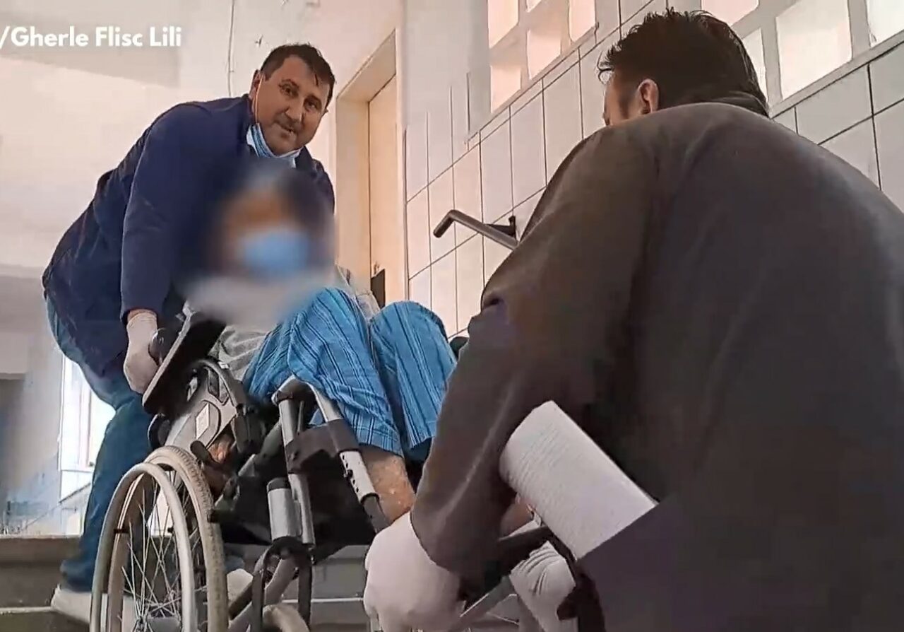 VIDEO | Scene revoltătoare într-un spital din Reșița! Pacienții imobilizați sunt cărați pe brațe de infirmieri pentru că în clădire nu există lift