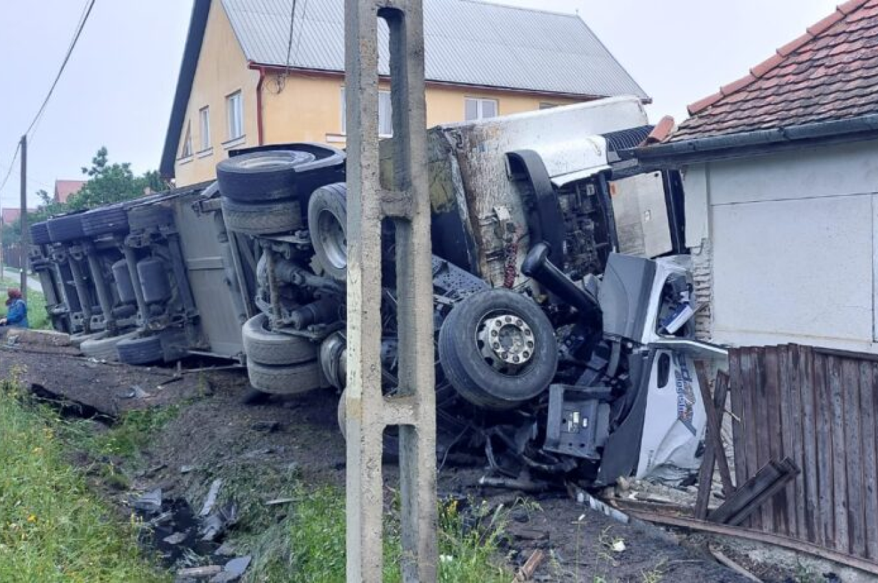 ACCIDENT cumplit pe DN 12/E578. Șoferul unui camion a scăpat „mastodontul” de sub control și s-a răsturnat peste o casă din Harghita