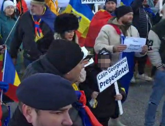 O femeie și-a pus copilul să țină în mână o pancartă cu „Călin Georgescu președinte” / Ce prevede LEGEA pentru părinții care-și duc copiii la proteste