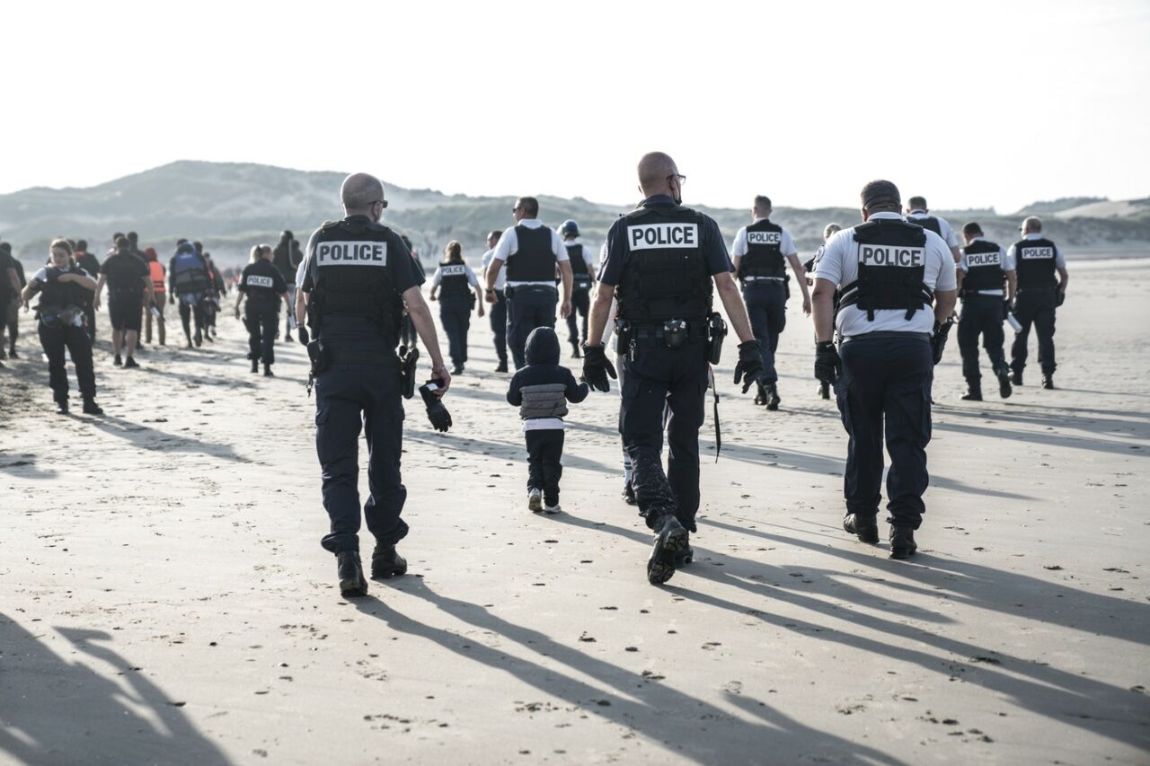 Momentul în care polițiștii francezi intră în apă și găuresc cu cuțitele o barcă de cauciuc plină cu IMIGRANȚI, surprins de reporteri